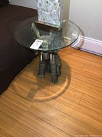 Glass top elephant table next to couch with lamp on top showing minor wear