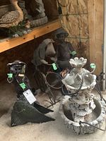 Wide view of garden ornaments including the fountain, dog on bike planter, and boy figurines