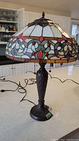 Full view of the metal lamp with stained glass shade on a kitchen counter, showing the decorative pattern and metal base.