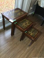 Set of 3 wood nesting tables with decorative cityscape tops visible; arranged largest to smallest, showing size range and nesting ability