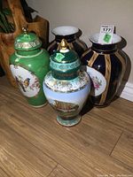 Four porcelain urns and vases arranged together on wooden floor showing overall size and design.