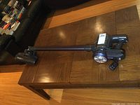 Full view of Dibea cordless stick vacuum with power head lying on wood table surface