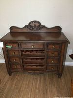 Frontal view of the wine cabinet showing six drawers on each side, a central drawer above, and three horizontal racks for wine bottles at center bottom.