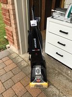 Front view of black Bissell ProHeat Pet carpet cleaner with visible cleaning solution tank and power control dial at bottom front.