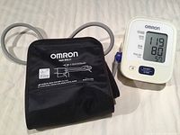 Omron digital blood pressure monitor and black adjustable cuff with grey tube, cuff size labeled 22-42 cm.
