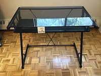 Front view of the glass top computer desk with black metal frame and pull-out keyboard shelf.