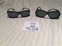 Two pairs of black framed polarized sunglasses on a white sheet with a note labeled Light Limiting Sunglasses