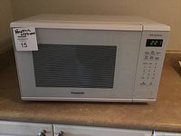 Front view of Panasonic white microwave on kitchen counter with LED display showing time 2:21.