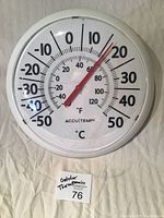 White round outdoor thermometer with red needle, dual temperature scale in Celsius and Fahrenheit, about 13 inches across, showing approx 13°C.