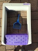 Top view of ScoopFree device showing the litter tray frame, integrated rake system, purple lid with paw prints, and blue scoop inside.