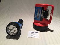 Blue and red Dorcy flashlights side by side on fabric surface showing flashlight lenses and packaging tag
