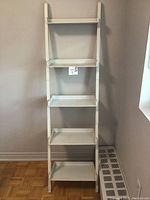 Front view of a white 5-shelf vertical shelving unit with flat rectangular shelves.