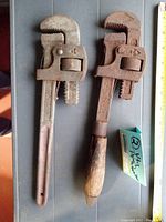 Two 14 inch vintage WALWORTH pipe wrenches, one with metal handle, one with wooden handle showing wear and patina.