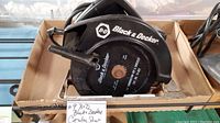 Black & Decker circular saw placed in a cardboard box, clearly showing the handle, blade guard, and electrical cord.