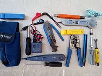 Full view of cable installation tools laid out showing Fluke 200EP Inductive Amplifier, cablematic wrench, yellow cable prep tool, cutters, Tempo pouch, and screwdrivers.