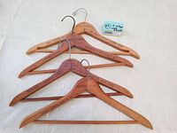 Four vintage men's wooden hangers with metal hooks arranged on a white surface. Shows overall condition and layout of hangers.