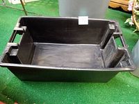 Black plastic rectangular container with handles shown from above, interior visible.