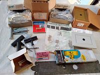 Overview of lot with key safe, garage door pulls, door viewer, and other hardware items spread on surface