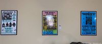 Four framed posters mounted on a wall including The Monkees, Rocky Horror Picture Show, and Lollapalooza '96