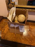 Open cardboard box containing several baseballs and white envelopes.