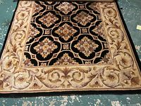 Full view of rectangular beige and brown floral patterned area rug laid out flat on floor.