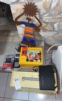 Lot items arranged on floor and against wall - sewing machine, cameras, calculator, metal art figure