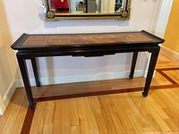 Full view of the console table showing the burl wood top and dark frame against a wall with a mirror above.