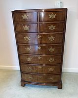 Front view of tall chest of drawers showing curved front and brass hardware