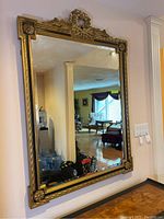 Full view of the large rectangular mirror hung on a wall reflecting a room interior.