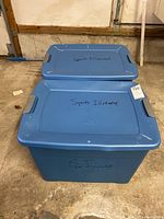 Two blue plastic storage totes labeled 'Sports Illustrated' stacked on garage floor