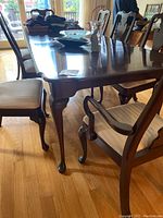Side view of the wooden dining table with chairs showing polished dark wood and cabriole legs with ball-and-claw feet.