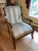 Front view of Thomasville upholstered armchair showing striped fabric and carved wood arms.