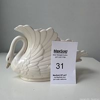 Front angled view showing detailed sculpted feather texture and swan handle forming the neck and head.