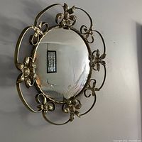 Front angled view showing convex mirror and brass floral frame.