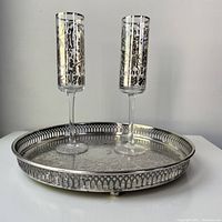 Gallery tray with ball feet and pierced border with two silver scrollwork flutes placed upright inside, showing overall condition and tarnish on tray