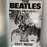 Front view of the mounted Beatles Revolver album poster showing the main black and white illustrated collage of the band members with text 'THE BEATLES', 'REVOLVER', and 'OUT NOW'