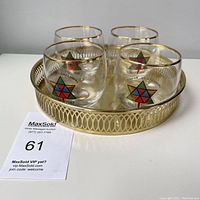 Four vintage Canada Centennial 1867-1967 roly poly glasses with gold rims and star emblems on a brass gallery tray.