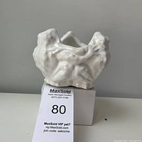 White vintage ceramic planter featuring two frogs hugging, placed on a white box with auction label visible.