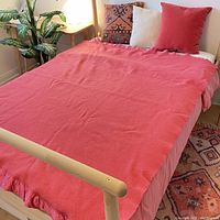 Pink wool blanket laid out on a double/full bed, showing overall condition and edge binding.