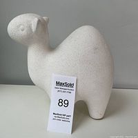 Side angle of white textured camel sculpture showing rough surface and shape