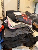 Stack of folded Beatles T-shirts, mostly dark colors with prints visible on top of stack.