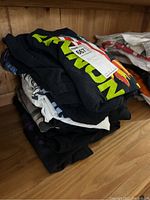 Stack of folded Beatles T-shirts in various colors including black, grey, and white, showing front prints partially.