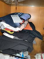 Close stacked view of folded assorted Beatles-related T-shirts mostly black and gray color tones.