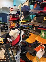 Full rack of stacked sports caps showing various colors and team logos.