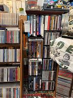 Full view of wooden rack filled with mixed CDs and DVDs tightly packed on multiple shelves.