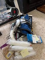 Photo showing an assortment of health items on carpet including massager, knee brace, cables, and wrapped packing materials.