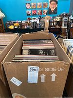 Box containing a selection of vinyl LP records upright in a cardboard box, spines visible