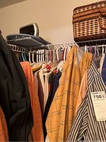 Closet rod with assorted men's shirts in various colors and styles including button-downs and tees