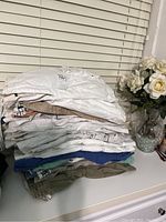 Stack of assorted men's shorts folded on a white surface, showing variety in colors and fabrics.