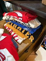 Stack of mixed colored sports team T-shirts folded.